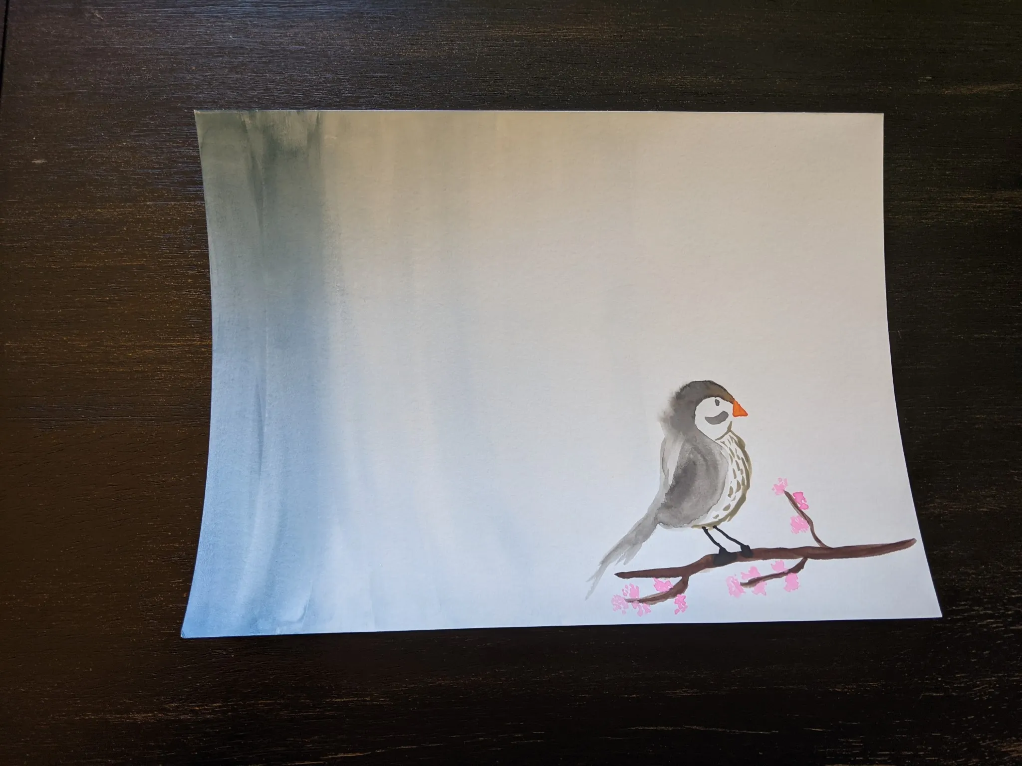 A watercolor painting of faded blue sky and a gray bird with a speckled chest and orange beak. The bird is on a tree branch with pink cherry blossoms.