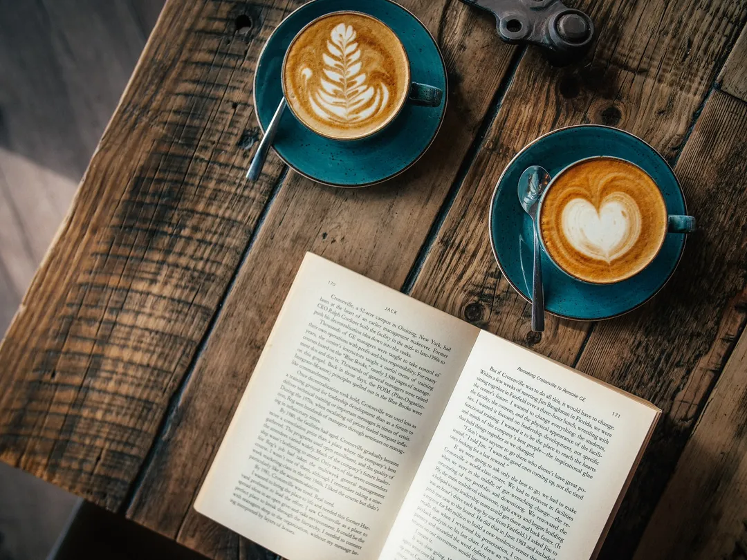 A cup of coffee beside an open book.